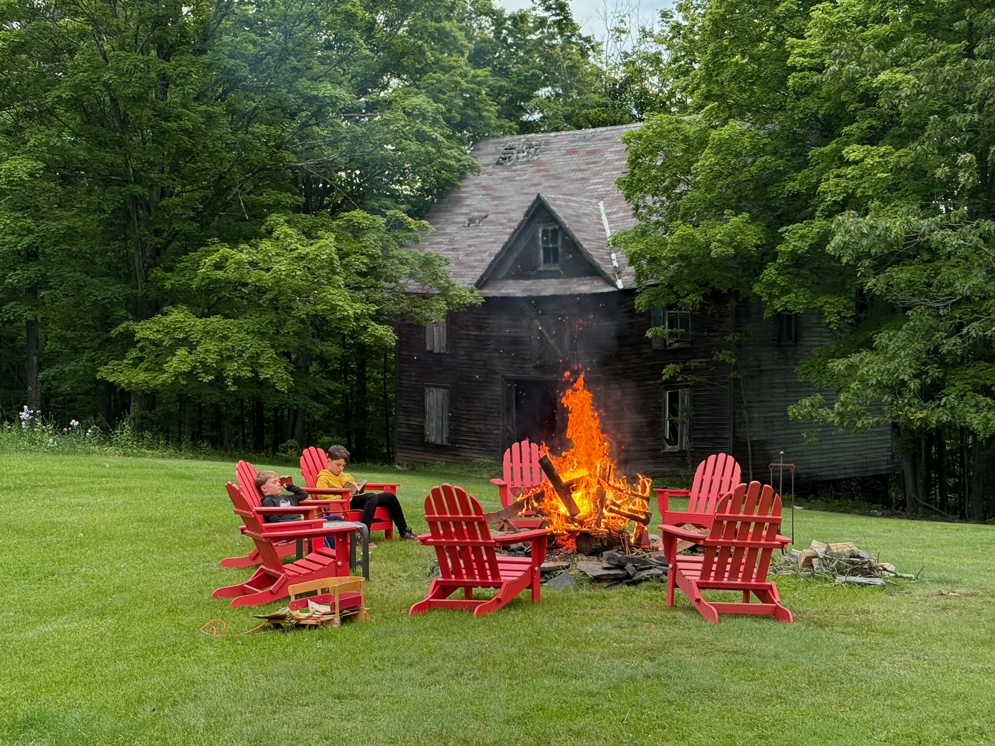 Daytime bonfire with the historic barn — red Adirondack chairs