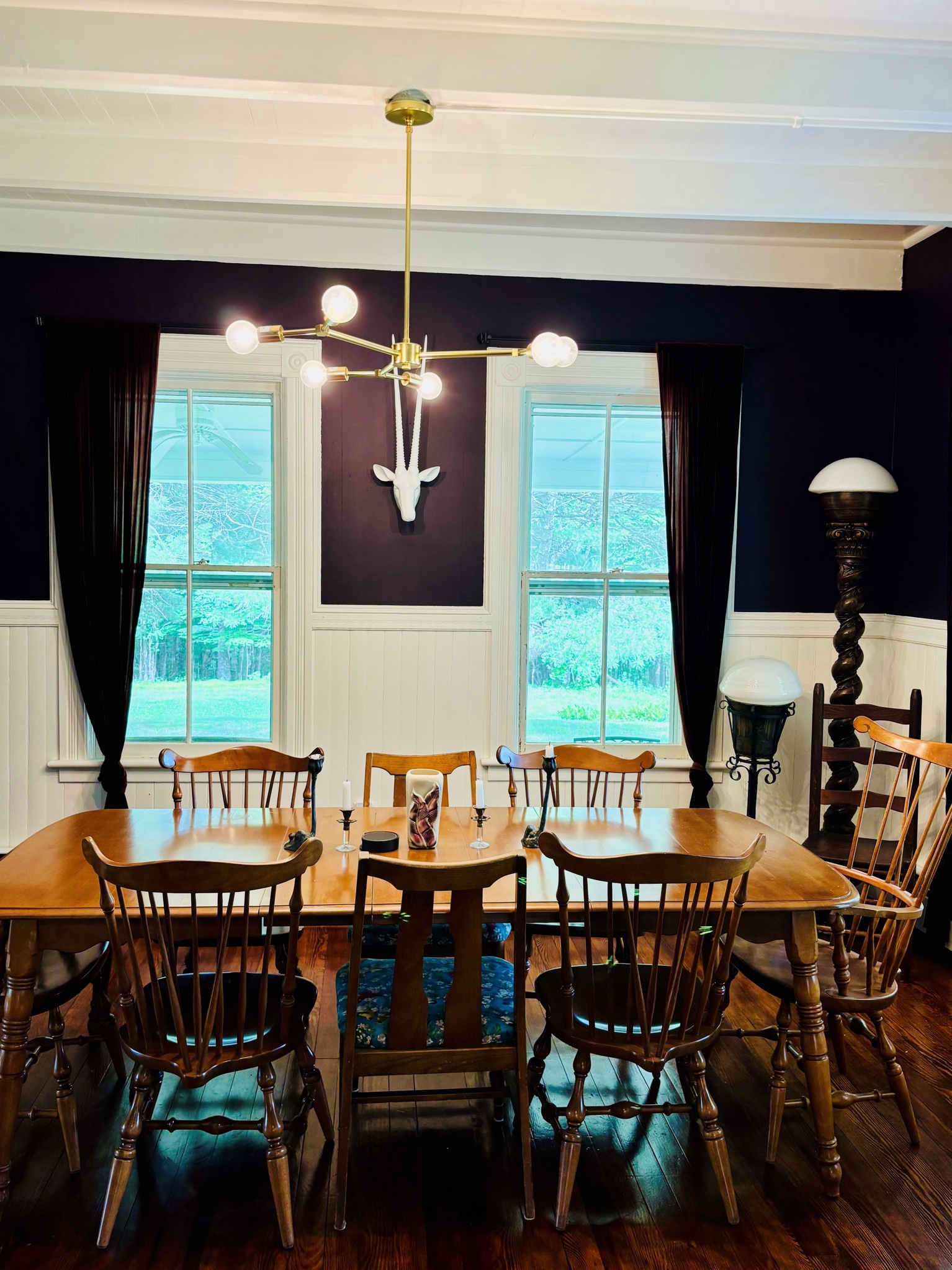 The dining room — deep plum walls, brass chandelier, table for ten
