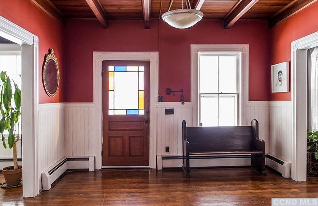 Entry hall showing original stained glass front door with geometric colored glass panels and original millwork surround