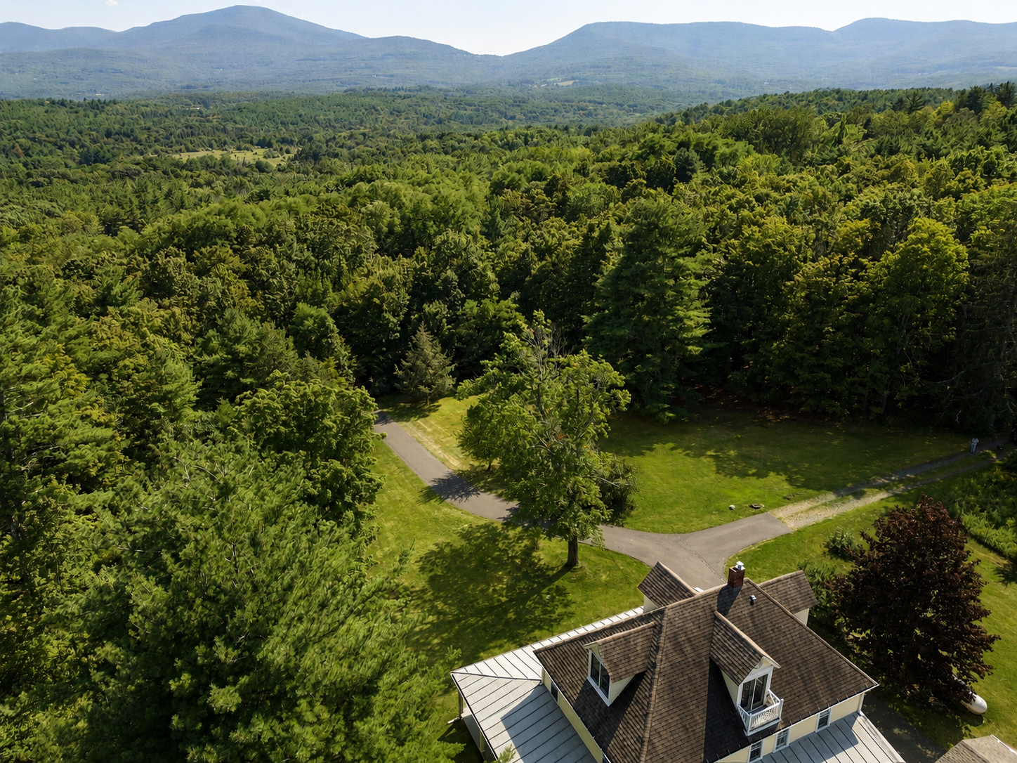 Aerial view of the farmhouse roofline against the surrounding forest and Catskill Mountains