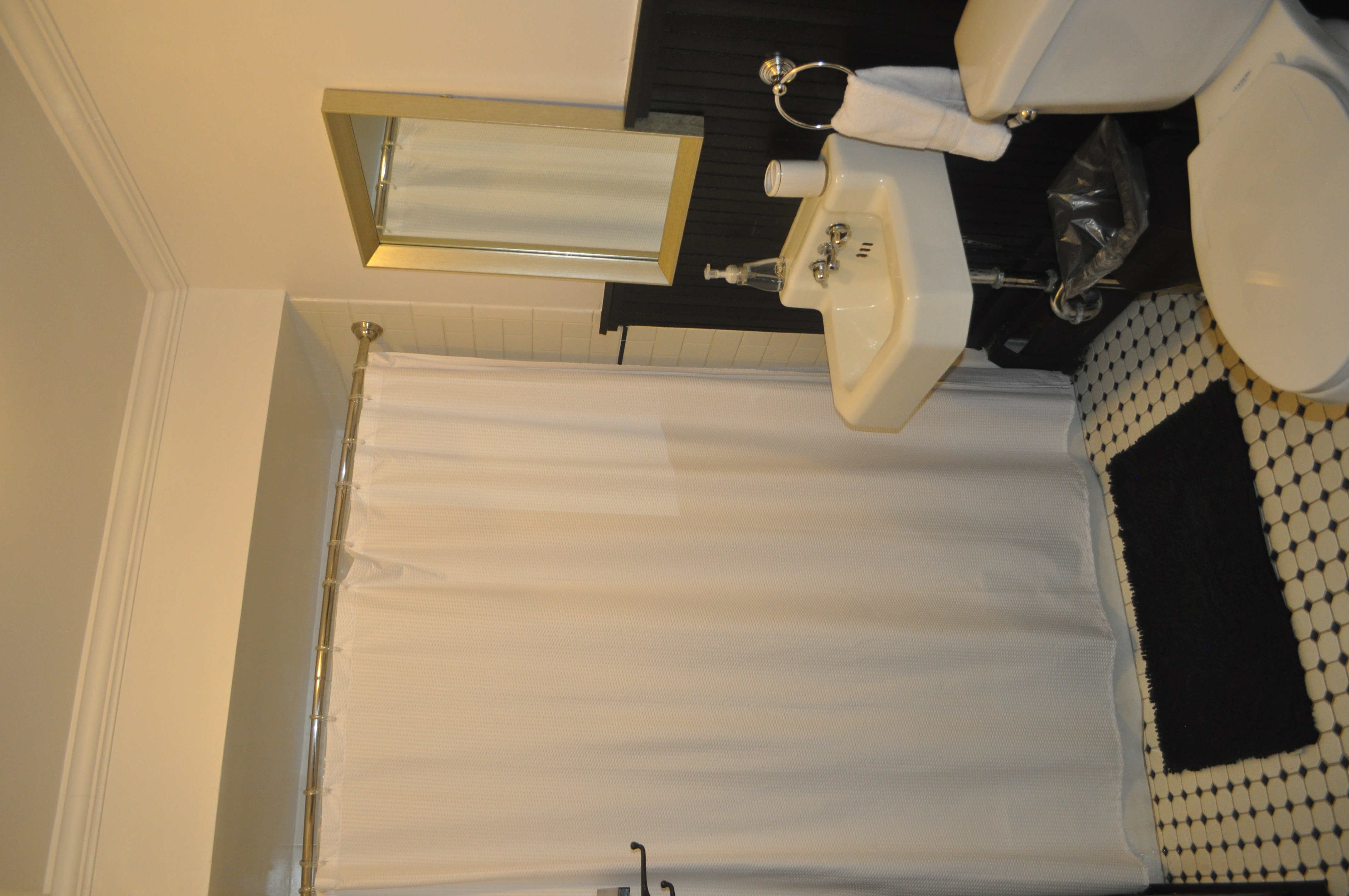 First floor bathroom with black beadboard wainscoting, white subway tile, and original penny tile floor