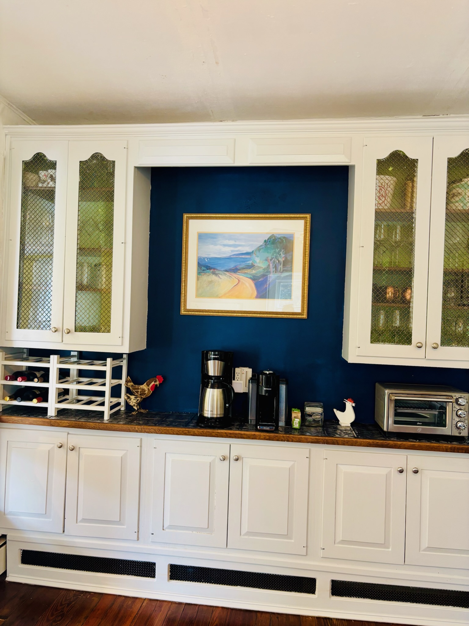 Kitchen with black lower cabinets, butcher block countertops, distressed white upper cabinets, and stainless gas range