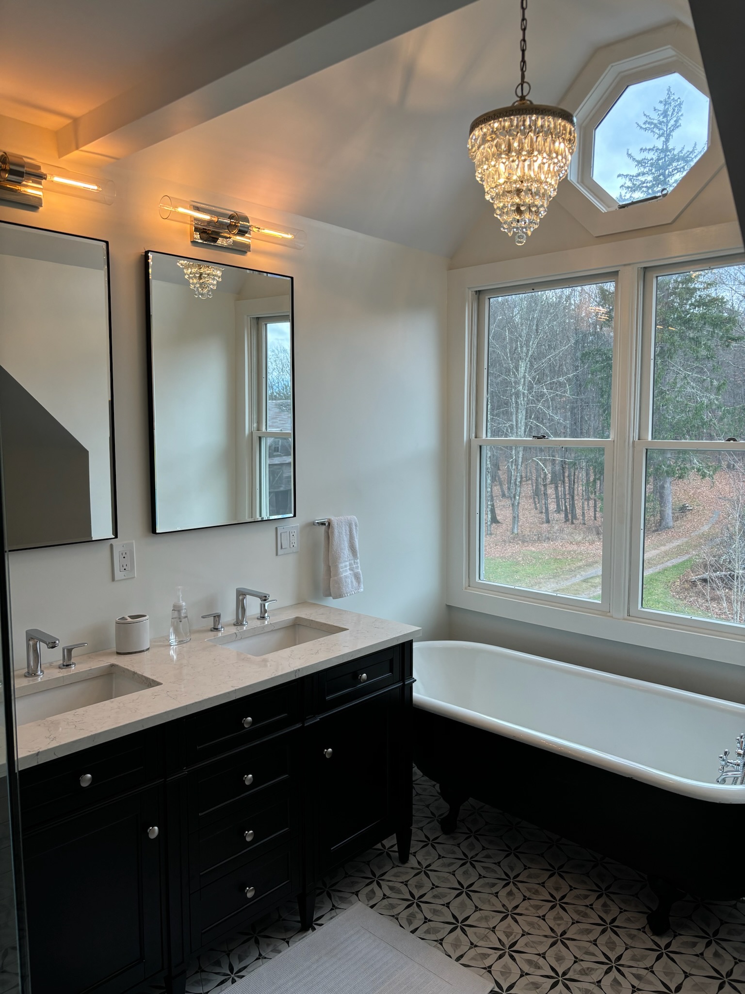 Master bathroom wide view showing glass shower, double vanity, clawfoot tub, and octagonal skylight