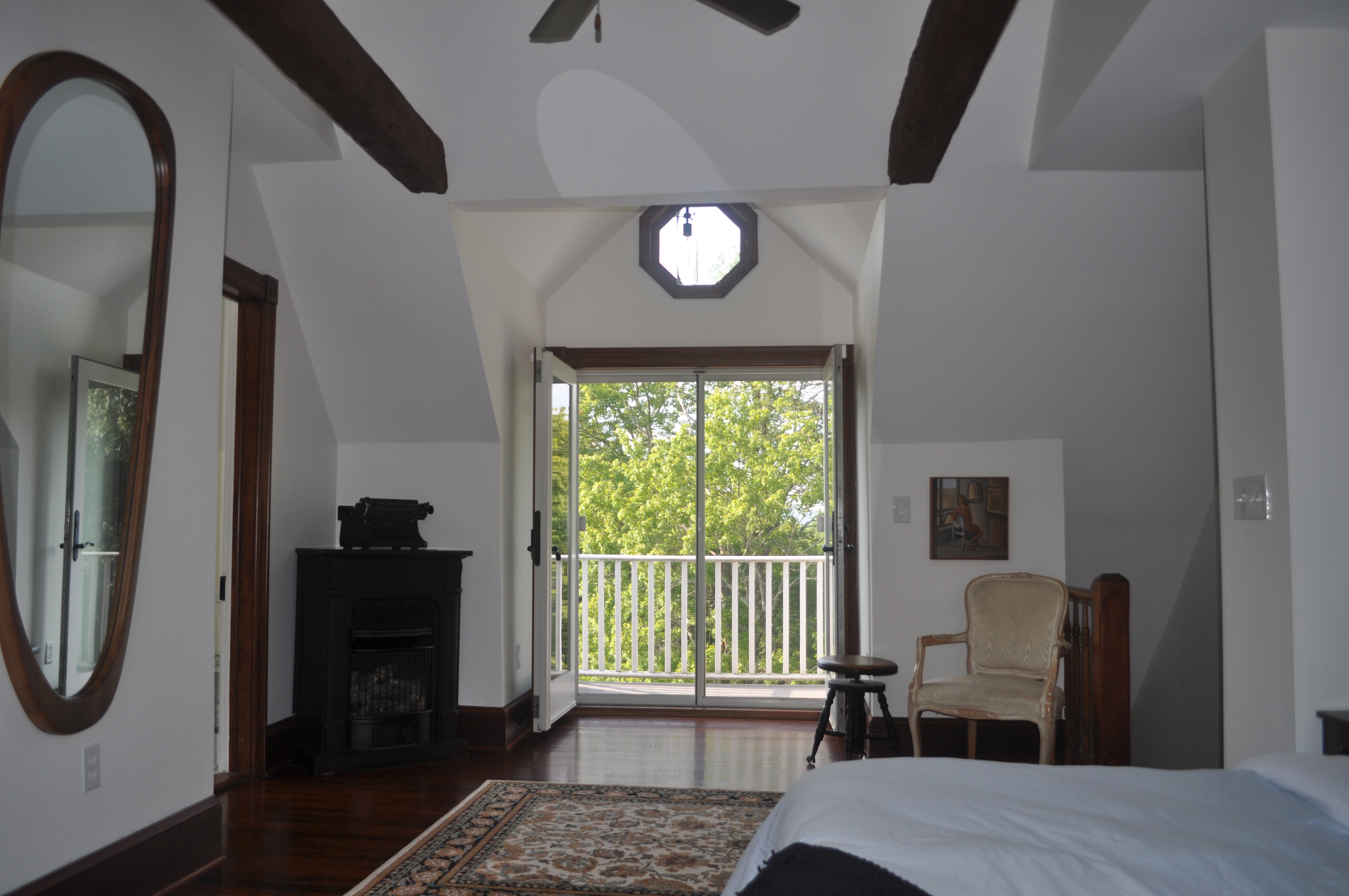Master bedroom alternate angle showing king bed, figurative painting above headboard, and exposed timber ceiling beams