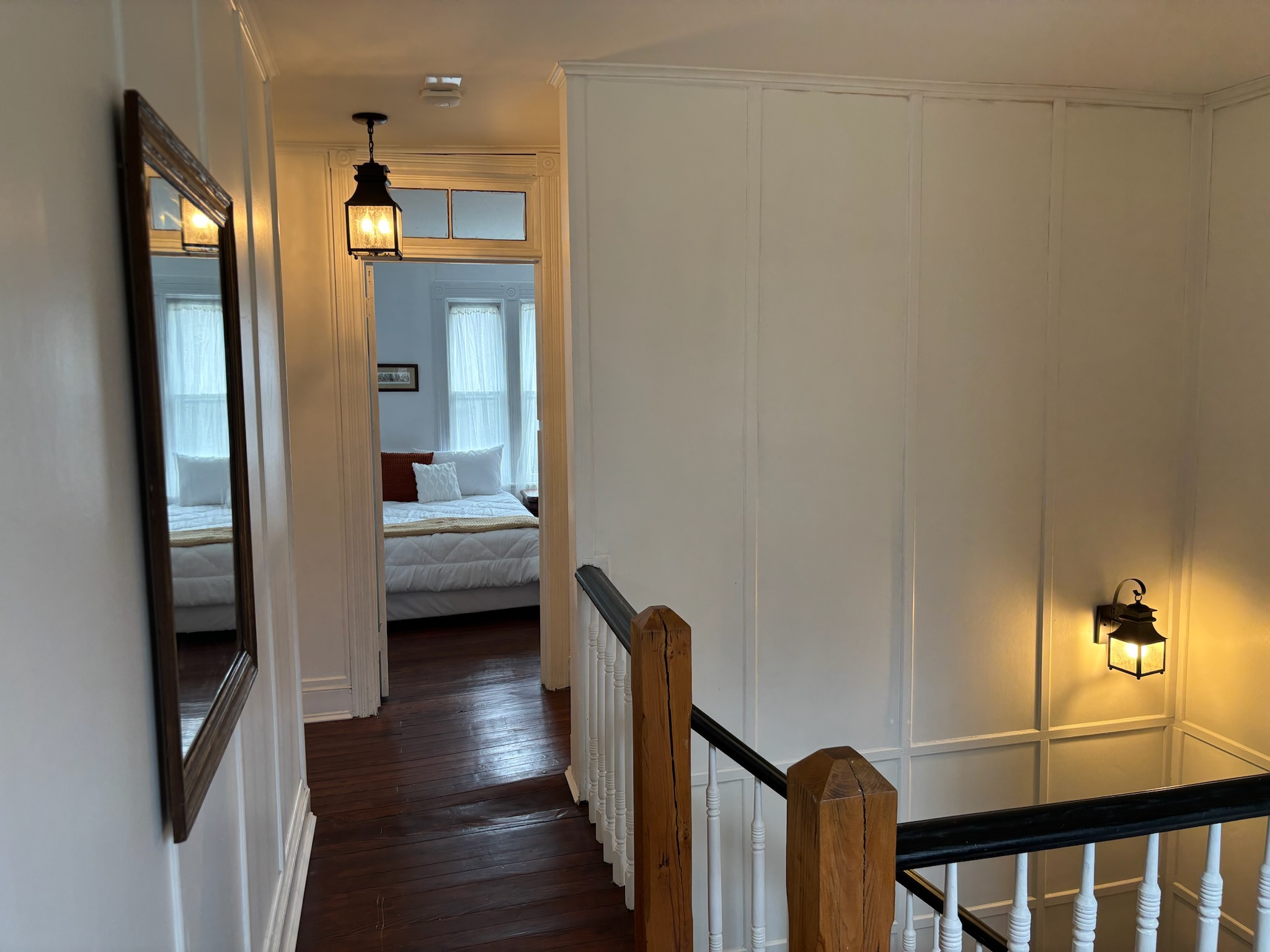 Second floor hallway with lantern lights illuminating the white paneled corridor